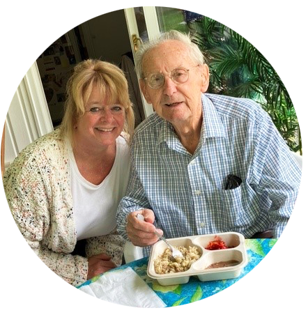 older man with a deliverd meal tray with a young woman sitting next to him