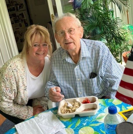 an older man eating a meal from a divided tray and a younger woman sitting next to him