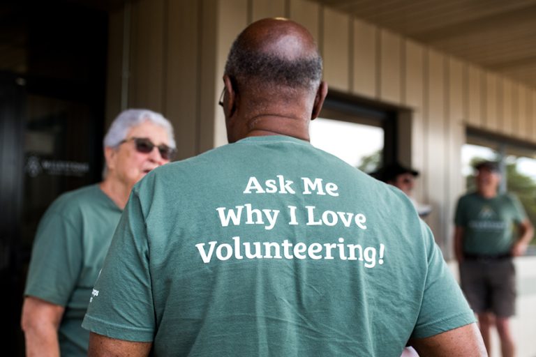 back of a man's shirt that says " Ask me why I love Volunteering"