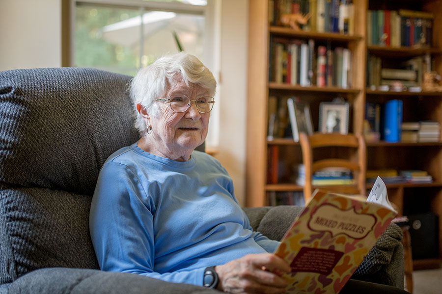 older woman sitting in comfortable chair reading