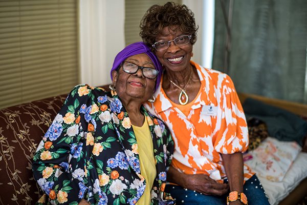 two women leaning into each other sitting on a couch