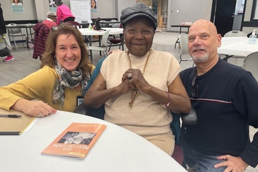 three people sitting together at a table smiling