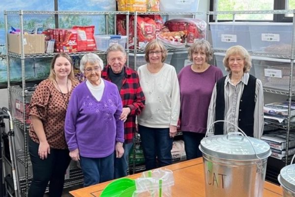 Six people standing in front of shelves with pet supplies, smiling.